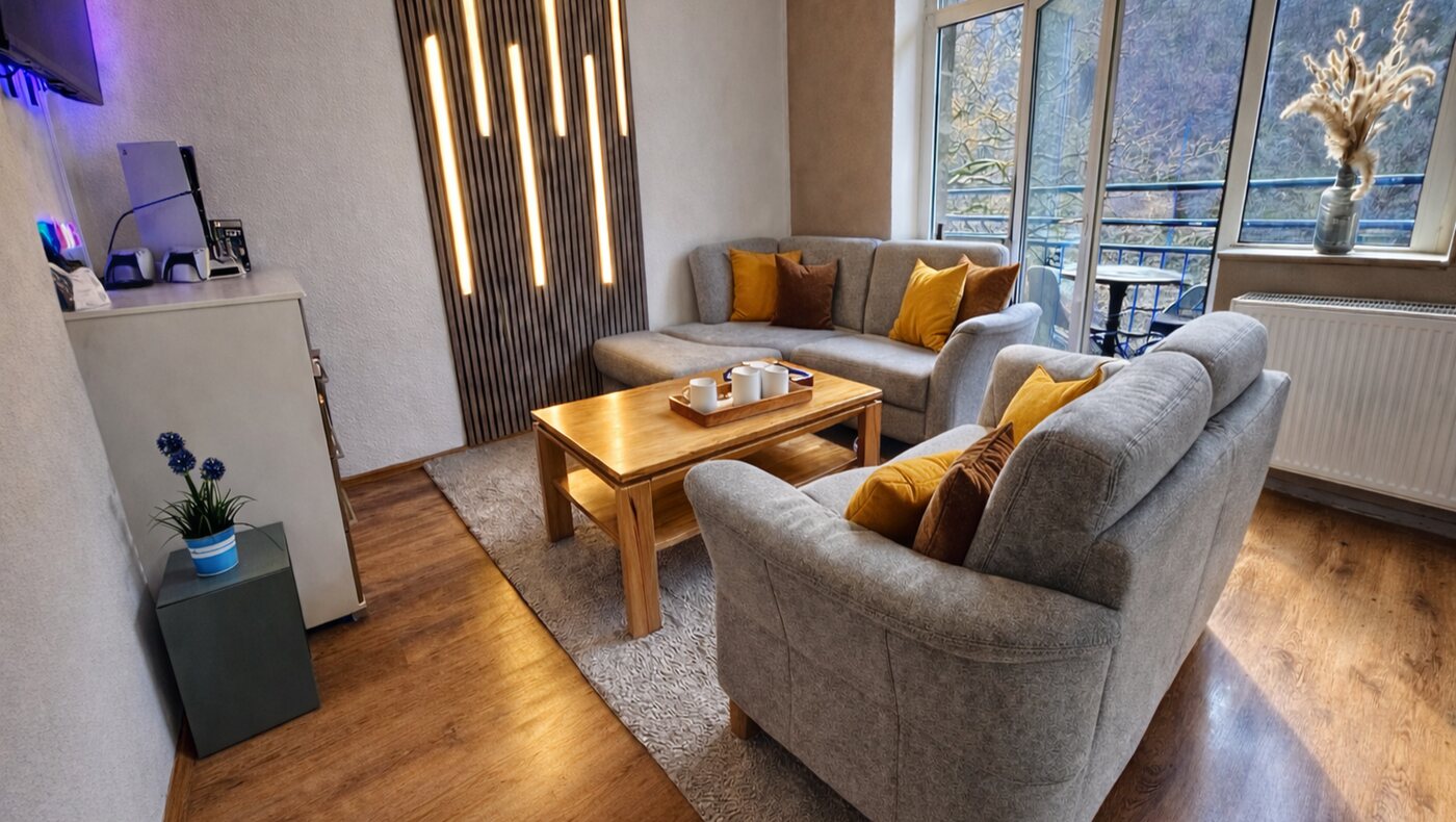 Wohnzimmer einer Monteurwohnung mit Sofalandschaft, LED-Lichtwand und PlayStation-Ecke